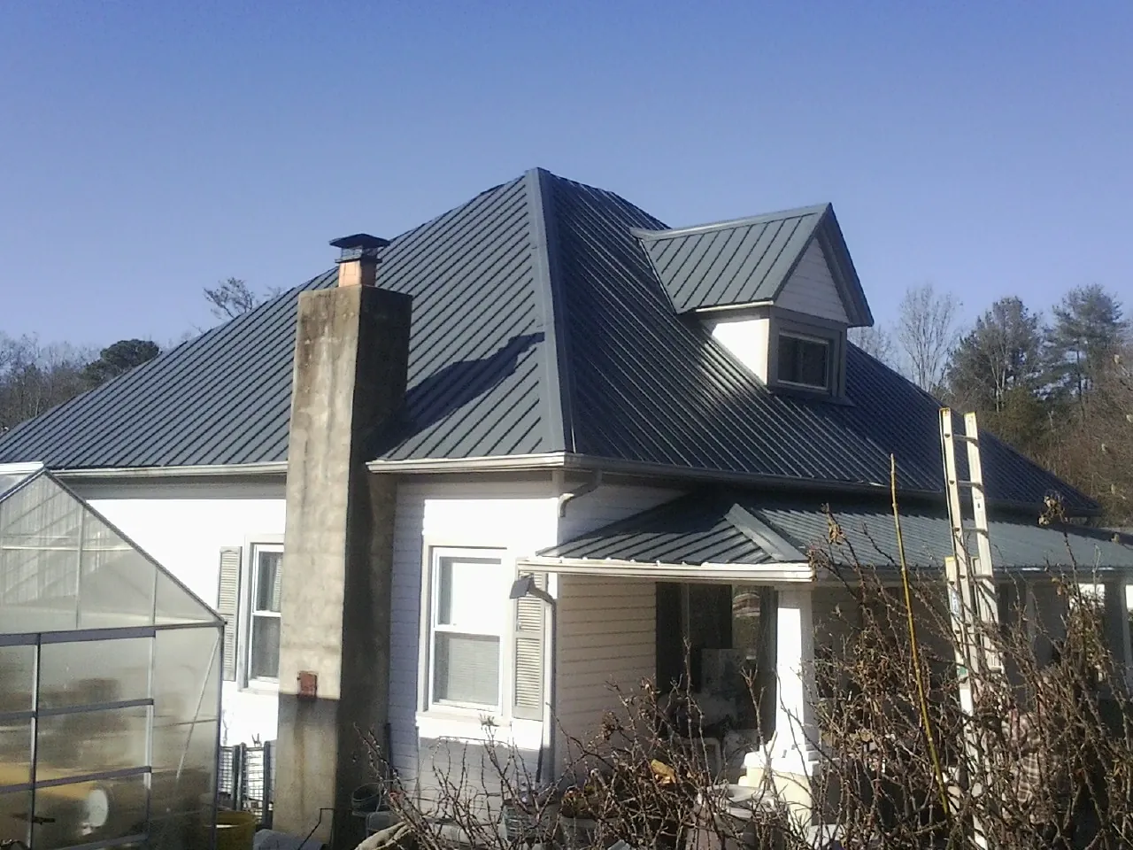Dark blue standing seam metal roof on a white farmhouse with dormer — Slate & Tile Roof Repair by Roofing Brothers in Francisco