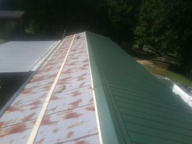 Old rusted panels beside newly installed green metal roofing — Wind Damage Roof Repair by Roofing Brothers in Francisco