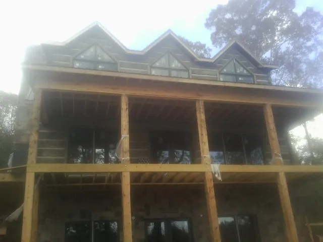 Dormers and porch framing on a large log home under construction — Roof Coating work by our crew in Francisco