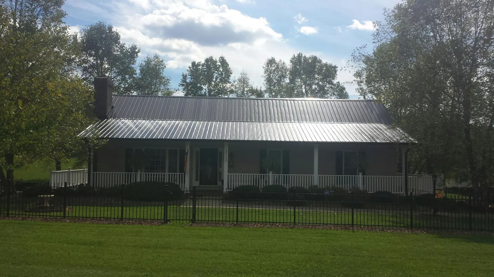 Gray metal roof on a brick ranch with a full width front porch — Gutter Guard Installation work by our crew in Francisco