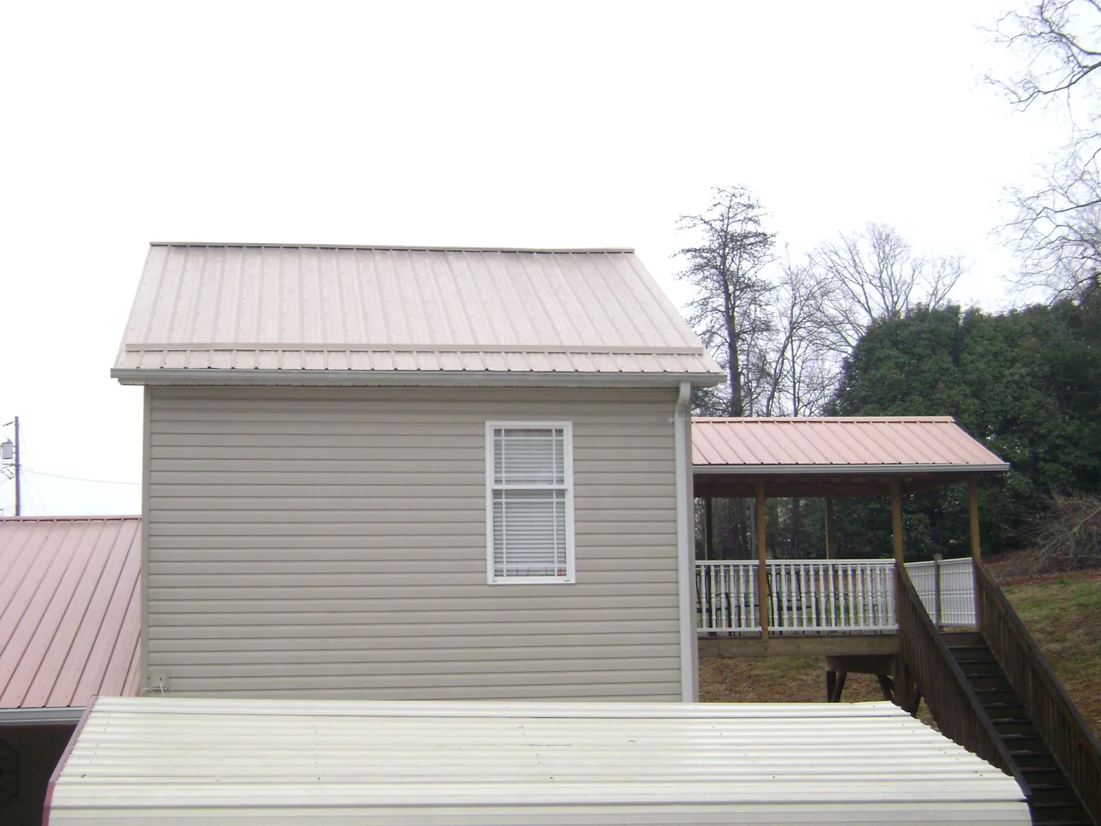 Tan metal roofs on a two story addition and attached porch, from a Roof Replacement job in Francisco
