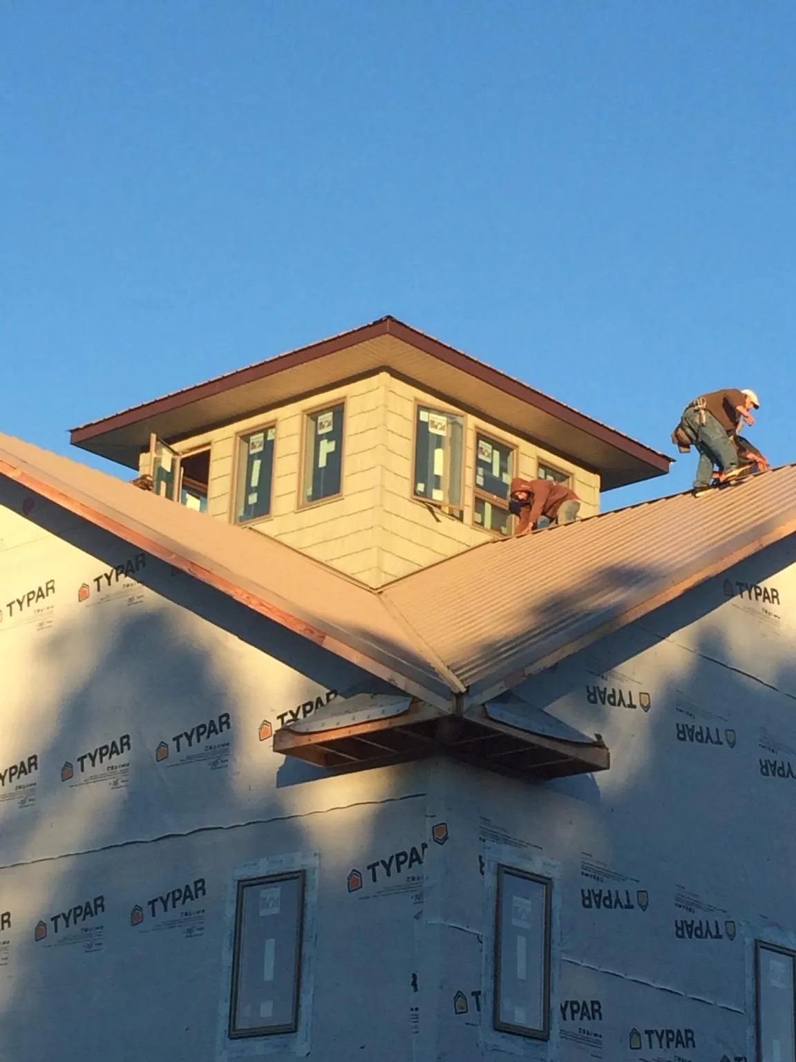 Roofers working around a rooftop cupola on a new metal roof at sunset — Roof Waterproofing in Francisco by Roofing Brothers